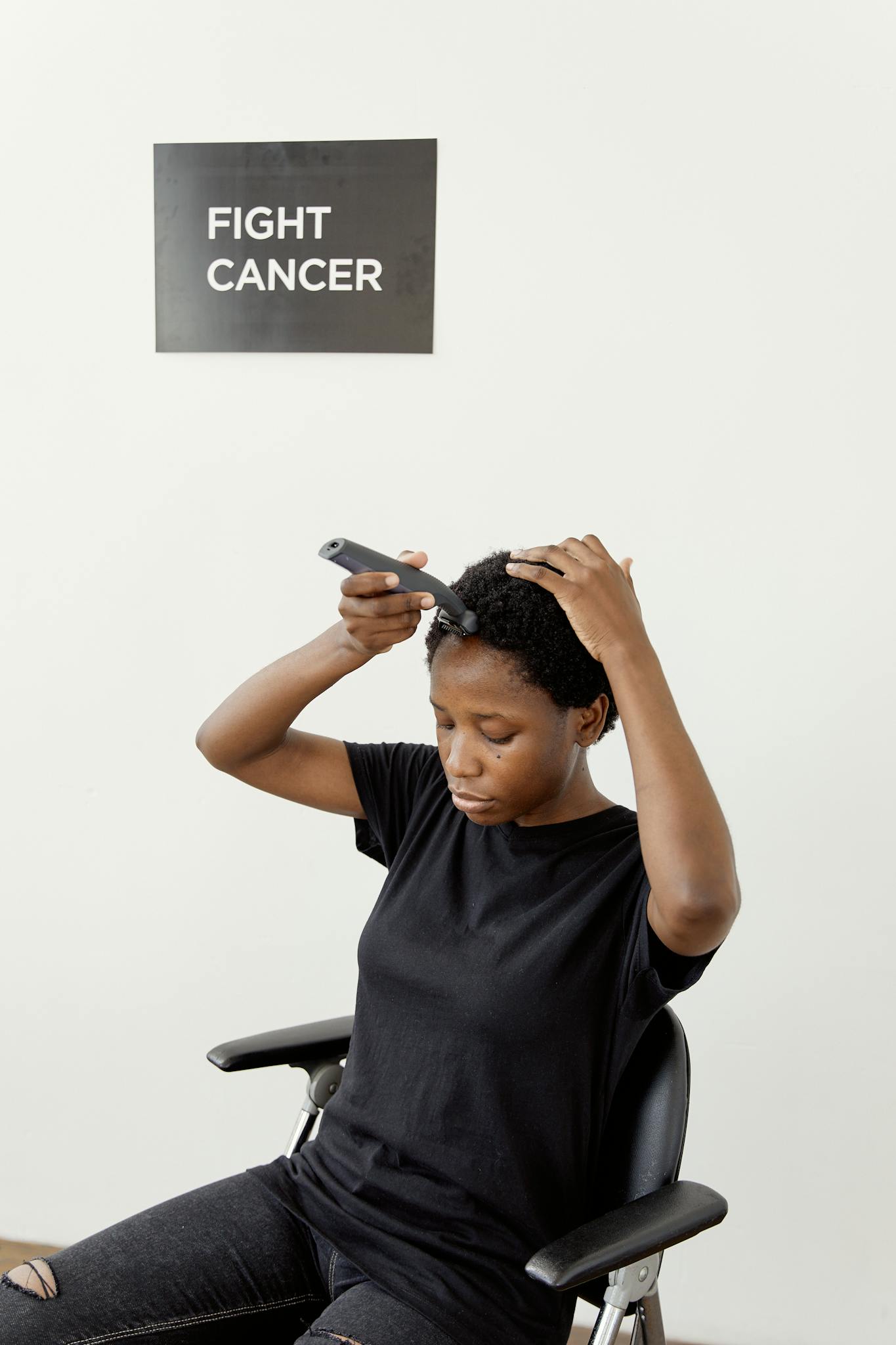 A black woman confidently shaving her head, symbolizing strength in cancer awareness.