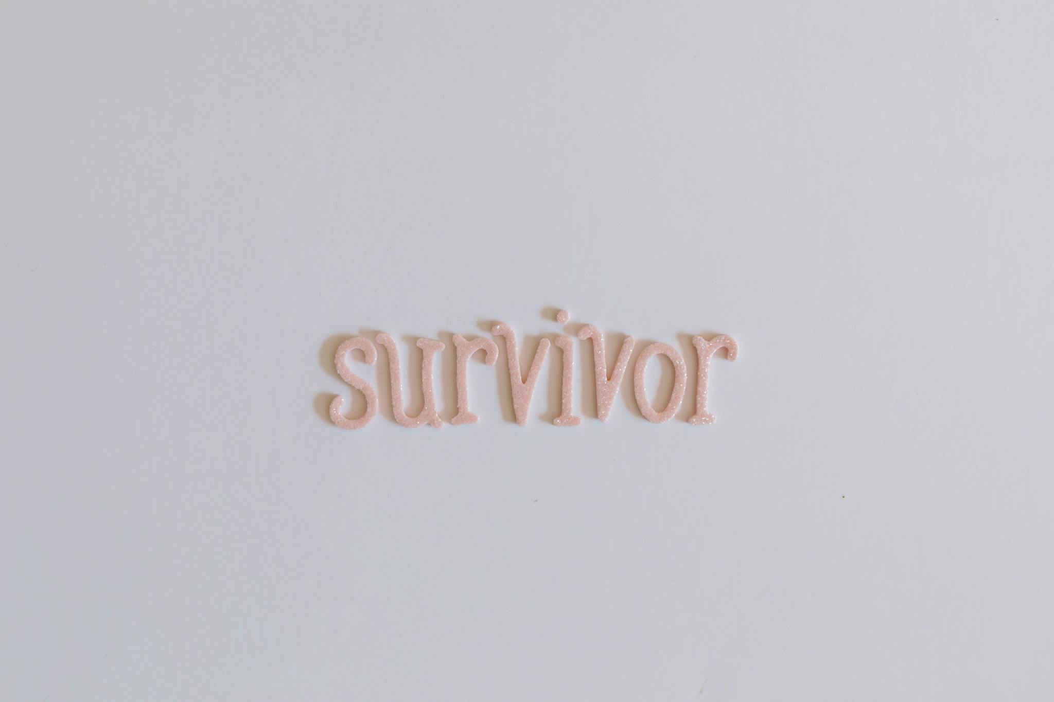 Close-up of the word 'survivor' in pink letters on a white background, symbolizing strength and resilience.